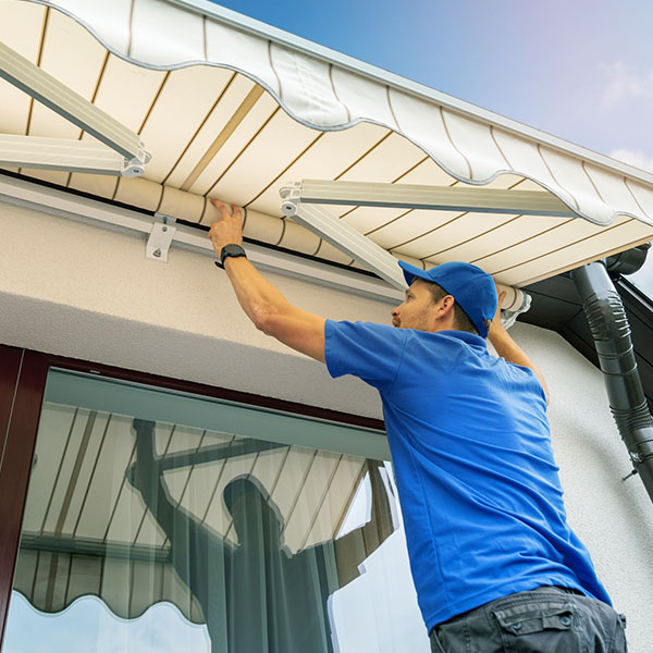worker install an awning on the house wall over the terrace window